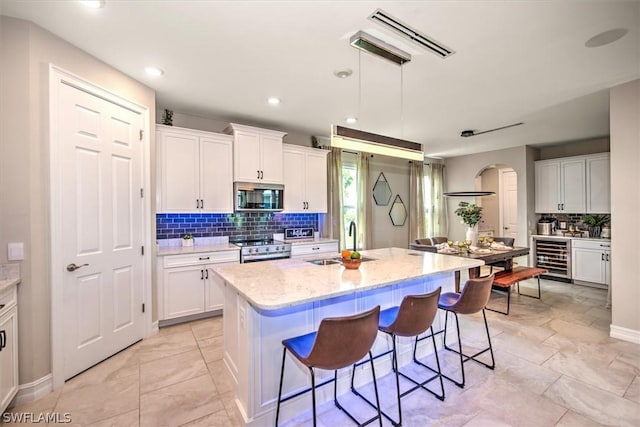 kitchen with white cabinetry, sink, an island with sink, and stainless steel appliances