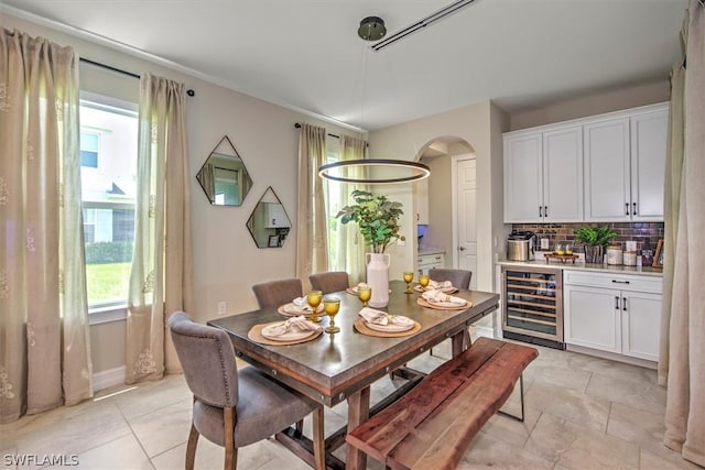 dining area with a wealth of natural light, light tile patterned floors, and beverage cooler