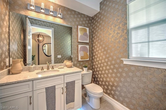 bathroom featuring tile patterned flooring, vanity, a chandelier, and toilet