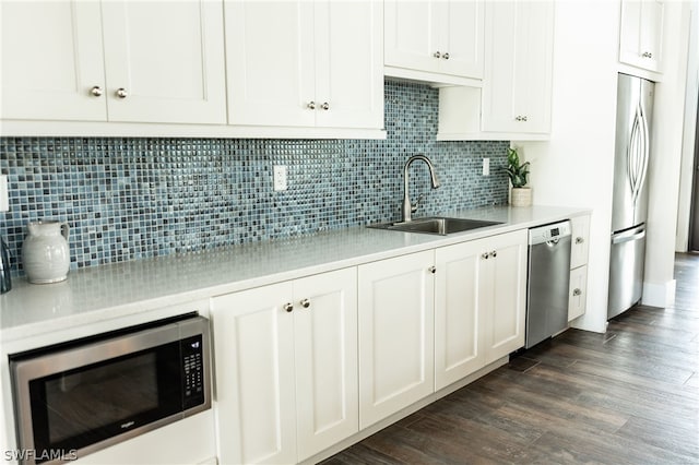 kitchen with appliances with stainless steel finishes, backsplash, dark hardwood / wood-style flooring, sink, and white cabinets