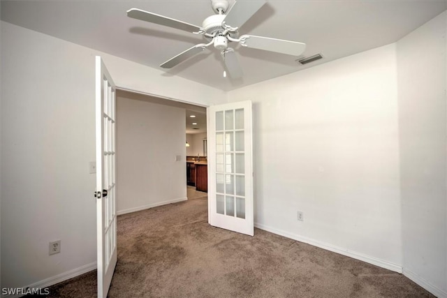 carpeted empty room with ceiling fan and french doors