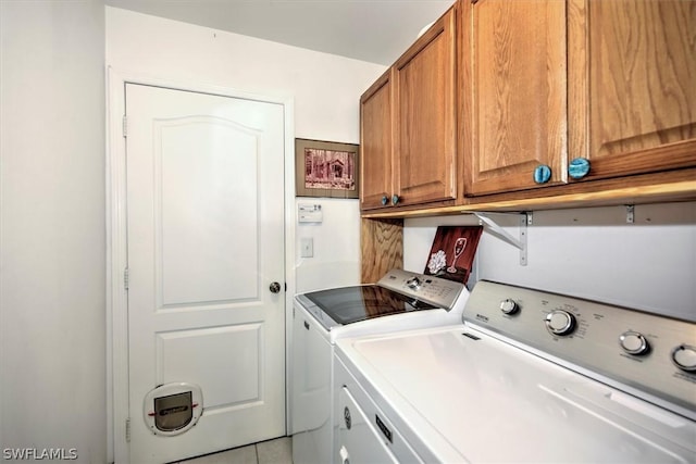 clothes washing area featuring cabinets, light tile patterned floors, and washer and clothes dryer