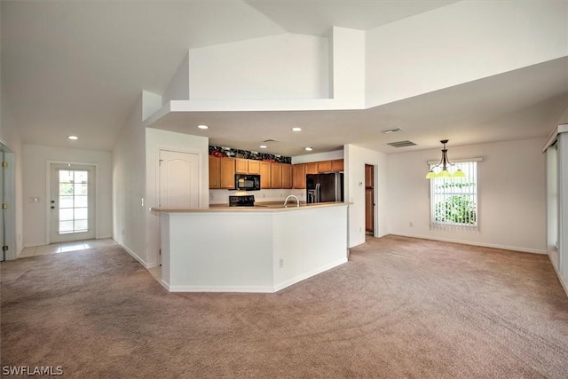 kitchen featuring pendant lighting, light carpet, plenty of natural light, and black appliances