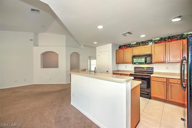 kitchen featuring light carpet, an island with sink, and black appliances