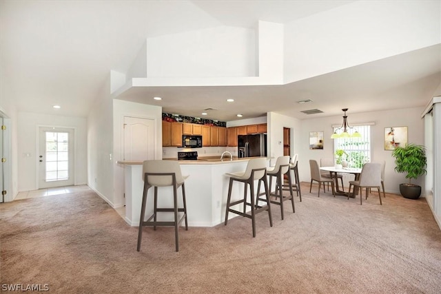 kitchen featuring light carpet, a kitchen bar, plenty of natural light, and black appliances