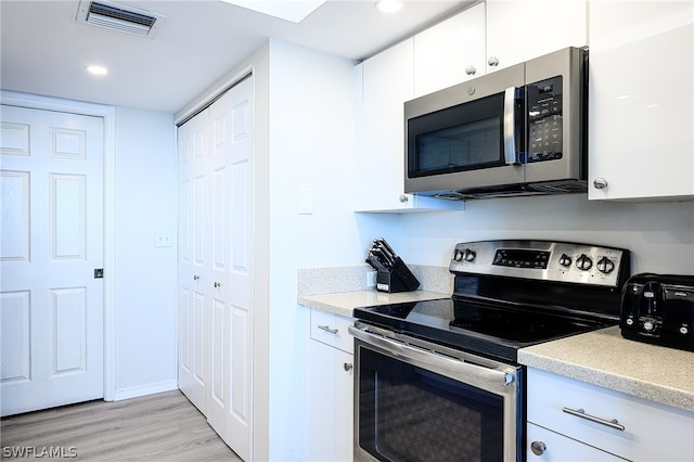 kitchen featuring light wood-type flooring, stainless steel appliances, and white cabinets