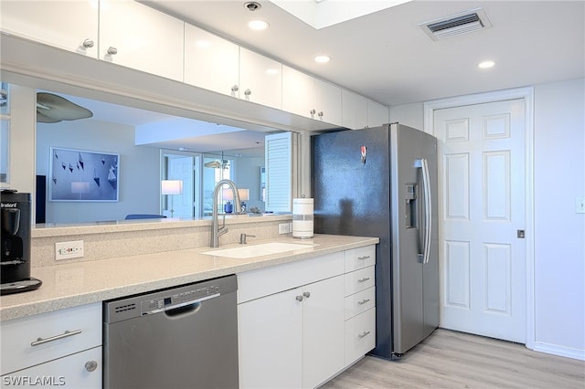 kitchen with white cabinetry, light wood-type flooring, light stone counters, stainless steel appliances, and sink