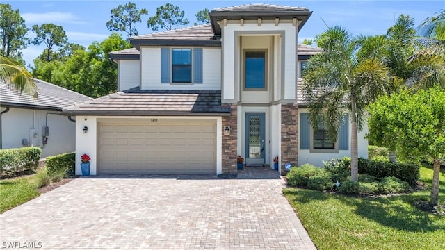 view of front of house with a garage, stone siding, a tiled roof, decorative driveway, and stucco siding