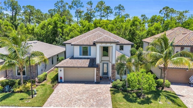 view of front of home featuring a front lawn, decorative driveway, a tile roof, and stucco siding