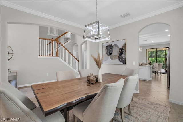 dining space with arched walkways, ornamental molding, stairway, and light tile patterned floors