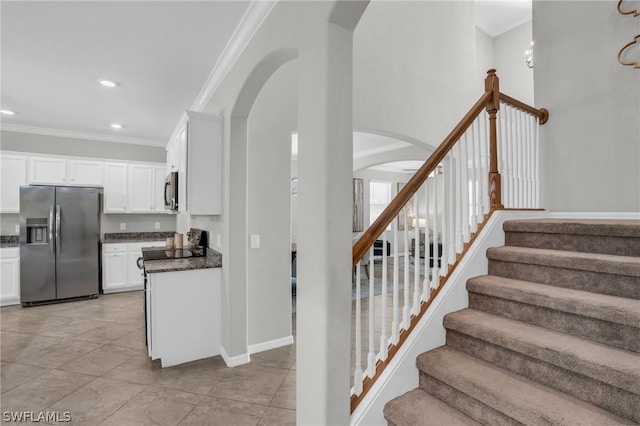 staircase featuring baseboards, arched walkways, crown molding, and recessed lighting