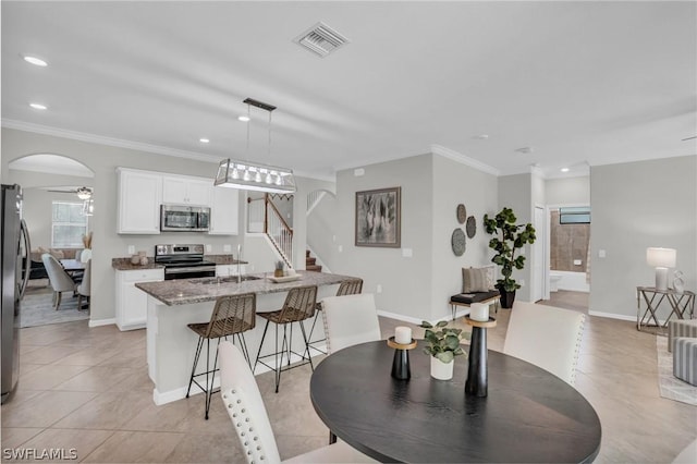 dining room featuring arched walkways, recessed lighting, visible vents, ornamental molding, and stairs