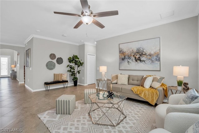 tiled living room with arched walkways, ornamental molding, a ceiling fan, and baseboards