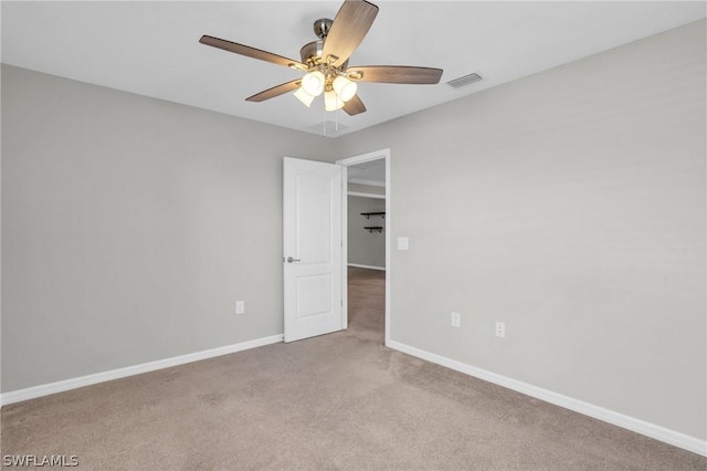 carpeted empty room featuring baseboards, visible vents, and ceiling fan