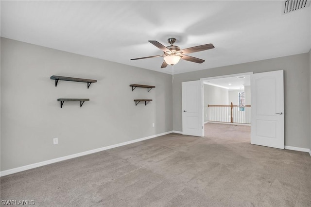 carpeted spare room with ceiling fan, visible vents, and baseboards