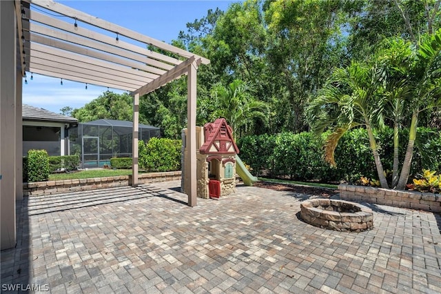 view of patio / terrace with an outdoor fire pit, a lanai, a playground, and a pergola