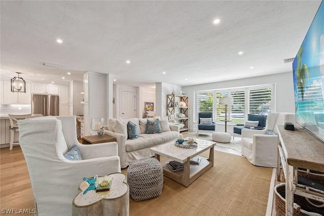 living room with a notable chandelier and light hardwood / wood-style flooring