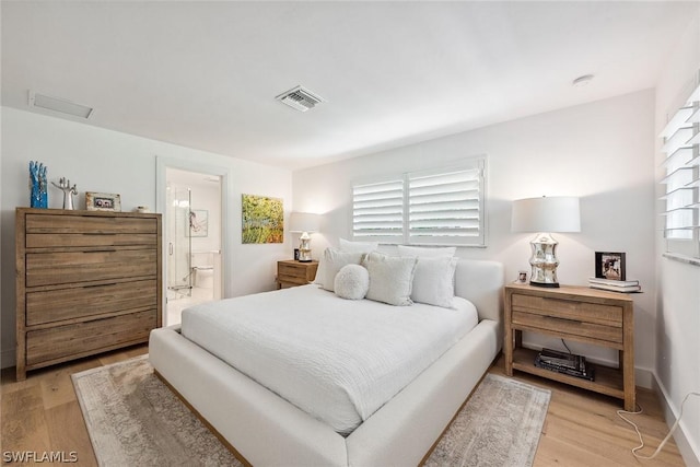 bedroom featuring light wood-type flooring and ensuite bath