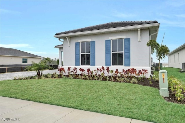 view of side of home featuring cooling unit and a lawn