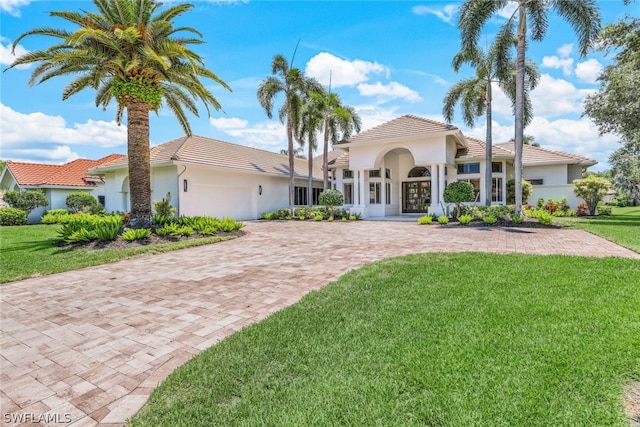 mediterranean / spanish home featuring a front lawn and a garage