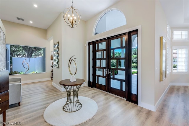 entrance foyer featuring a high ceiling, french doors, and light hardwood / wood-style floors