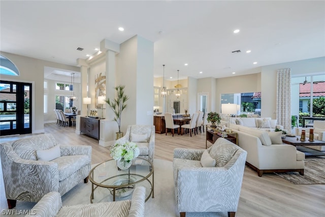 living room with a chandelier, a wealth of natural light, and light hardwood / wood-style floors