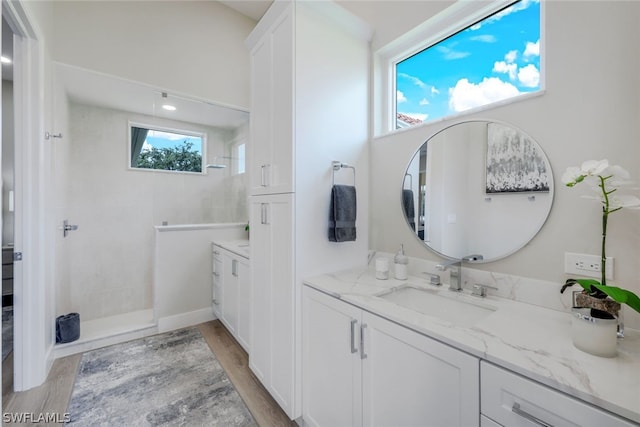 bathroom featuring vanity, wood-type flooring, and a tile shower