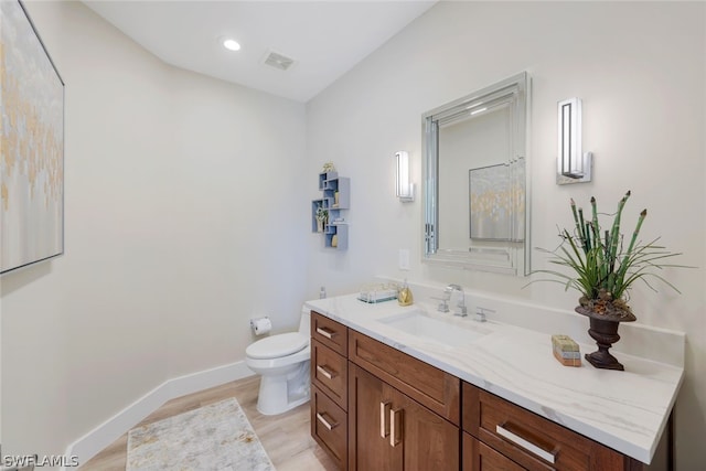 bathroom featuring toilet, vanity, and wood-type flooring