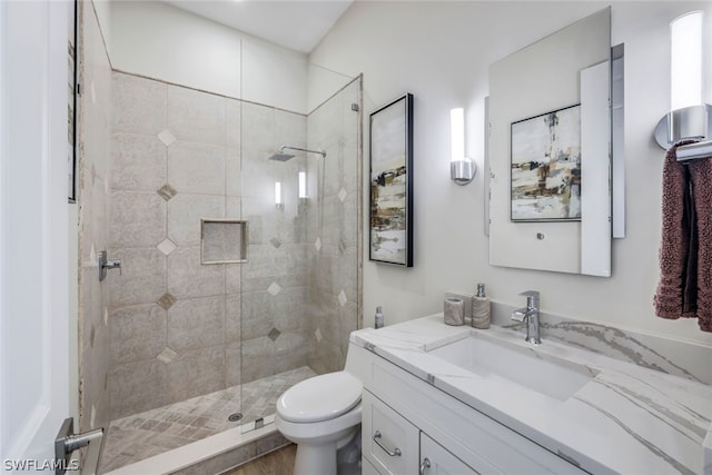 bathroom featuring hardwood / wood-style floors, vanity, toilet, and a tile shower