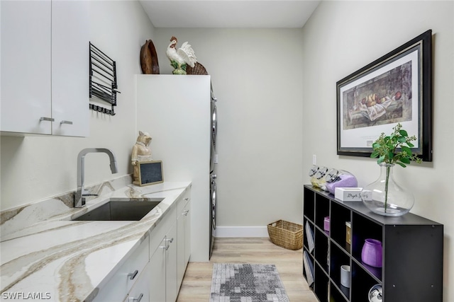 kitchen featuring white cabinetry, light hardwood / wood-style flooring, sink, and light stone countertops