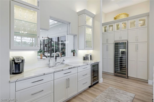 bar with white cabinetry, beverage cooler, sink, and backsplash