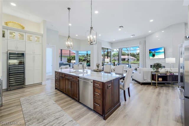 kitchen featuring decorative light fixtures, dark brown cabinetry, sink, stainless steel dishwasher, and beverage cooler