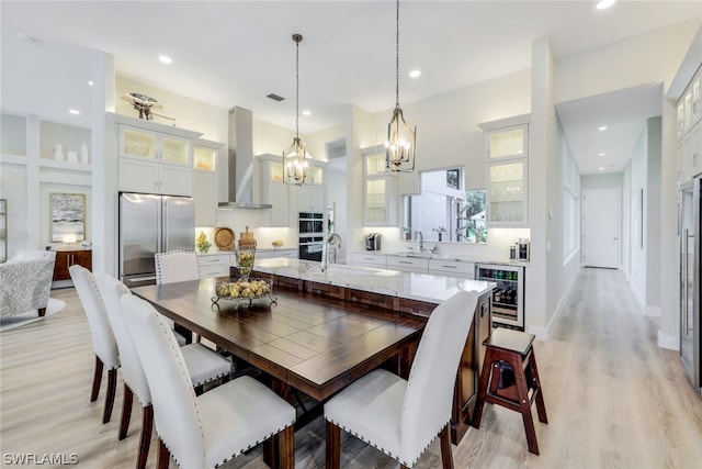 dining space with light wood-type flooring, sink, and beverage cooler