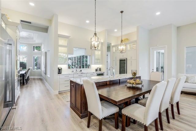 dining space with light hardwood / wood-style floors, beverage cooler, and sink