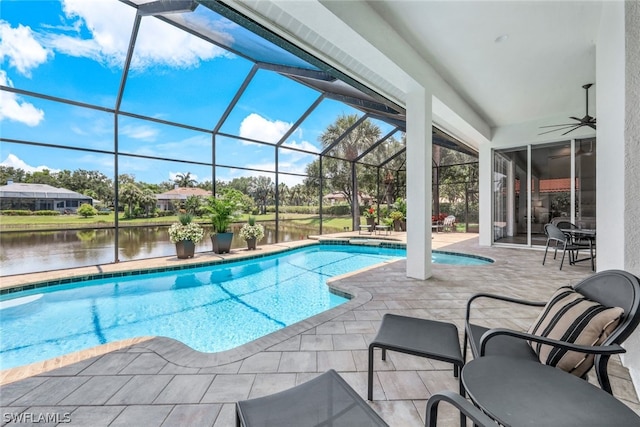 view of pool featuring glass enclosure, a patio area, a water view, and ceiling fan