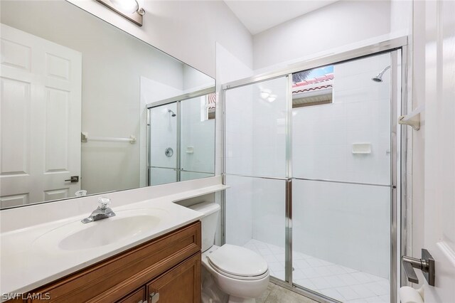 bathroom featuring vanity, an enclosed shower, and toilet