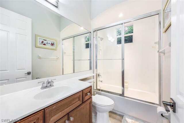 full bathroom with vanity, bath / shower combo with glass door, and toilet