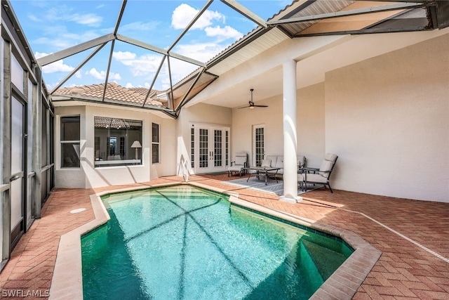 outdoor pool featuring glass enclosure, a ceiling fan, a patio, and french doors