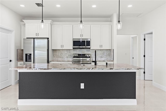 kitchen with white cabinets, pendant lighting, appliances with stainless steel finishes, and an island with sink