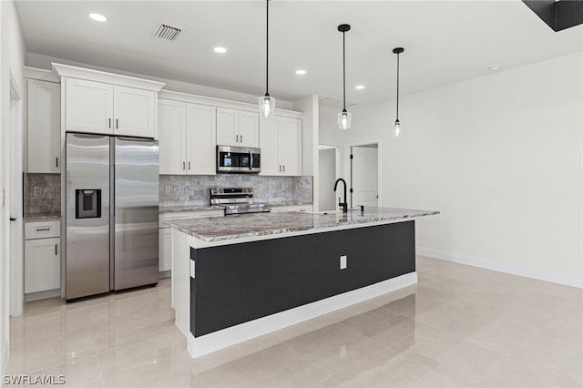 kitchen with decorative light fixtures, a kitchen island with sink, white cabinetry, and appliances with stainless steel finishes