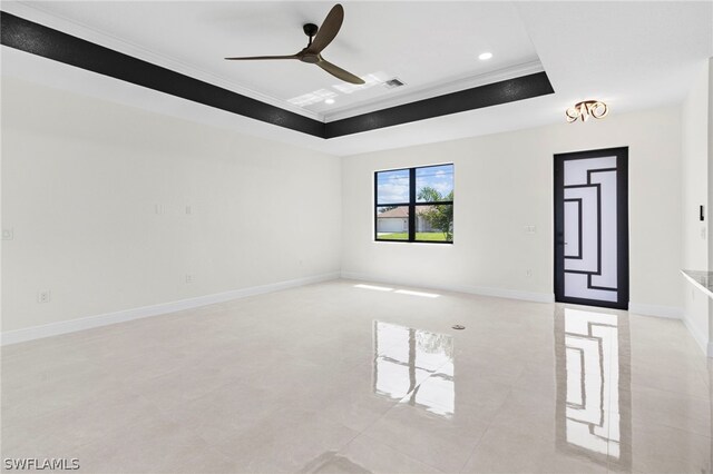 spare room with ceiling fan, a tray ceiling, and ornamental molding