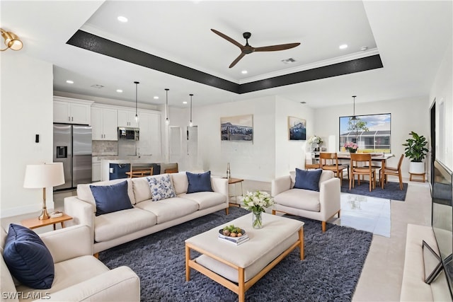 living room featuring ceiling fan, ornamental molding, and a raised ceiling