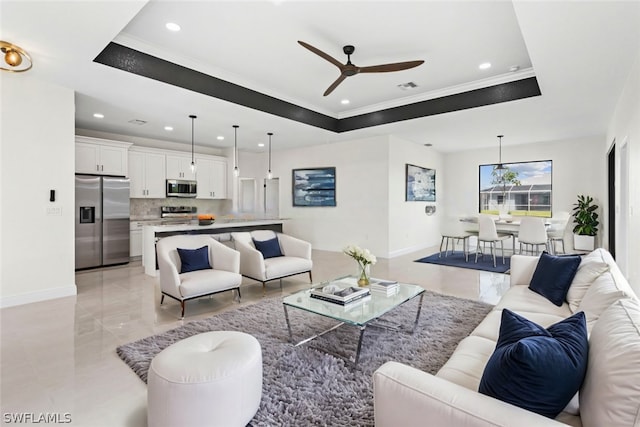 living room with ceiling fan, a tray ceiling, and crown molding