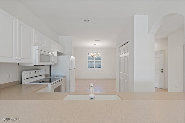 kitchen featuring white appliances, a chandelier, sink, white cabinetry, and pendant lighting