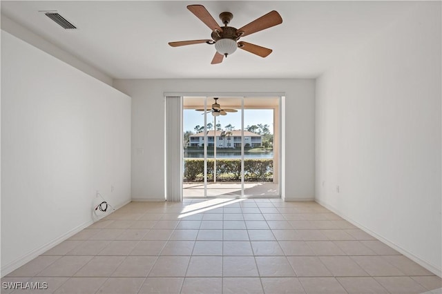 tiled spare room with a water view and ceiling fan