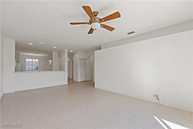 unfurnished living room with ceiling fan with notable chandelier and light tile patterned floors