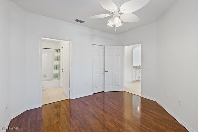 unfurnished bedroom with a closet, hardwood / wood-style floors, connected bathroom, and ceiling fan