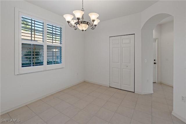 spare room with an inviting chandelier and light tile patterned floors