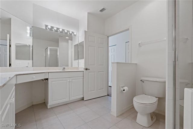 bathroom with tile patterned floors, vanity, a shower with shower door, and toilet