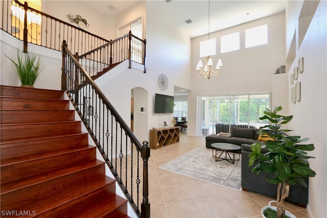 staircase with a high ceiling, a chandelier, and tile patterned floors